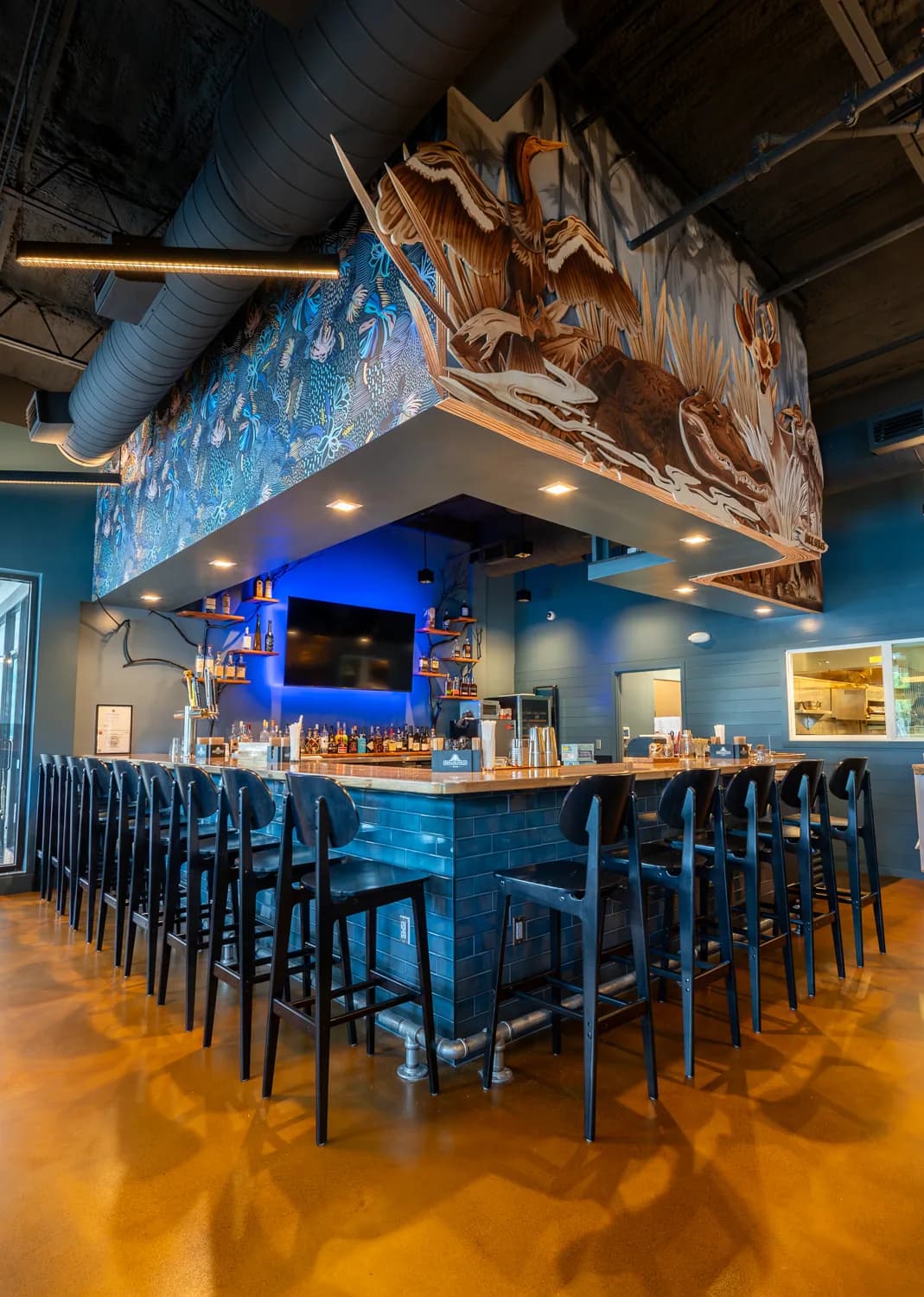 The Sweet Fish bar beneath its carved Florida wildlife mural of wading birds and palms.